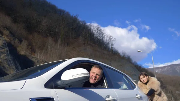 Due belle ragazze spingono la macchina rotta sulla strada. un uomo siede al volante — Foto Stock