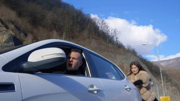 Dos hermosas chicas empujan el coche roto en la carretera. un hombre se sienta detrás del volante — Foto de Stock