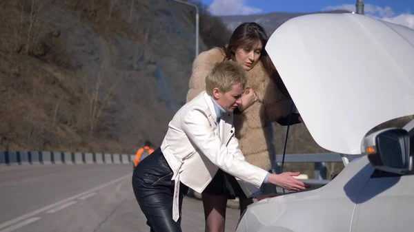 Two girls are charging the battery in a car standing on the side of the road — 스톡 사진