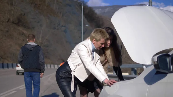 Mujer reparando el coche. Un hombre pasa por aquí, ignorándolos. humor . — Foto de Stock