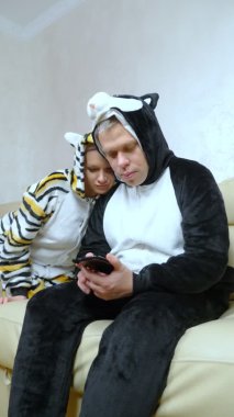 Dikey. Kigurumi kedisi içindeki bir kız kigurumi köpekli bir adamı okşar. 