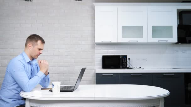 Üzletember használja a laptopját, miközben ül az asztalnál a konyhában — Stock videók