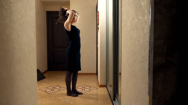 Girl makes herself a hair standing in front of a mirror at home — Stock Photo, Image