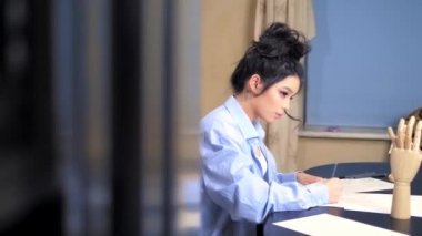 Güzel esmer kız ahşap bir mankenle eskiz çiziyor.