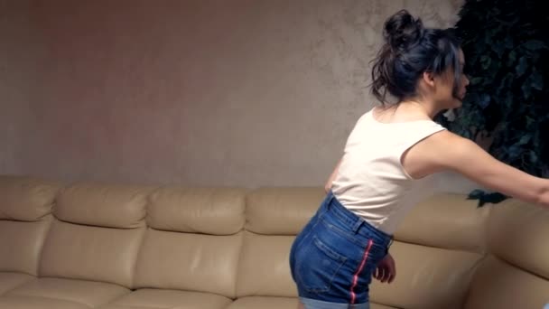 Schöne brünette Mädchen zieht sich zu Hause im Wohnzimmer ein Hemd an. Lebensstil — Stockvideo