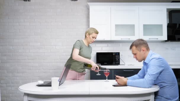 Ama de casa moderna y hombre de negocios descansando y bebiendo vino en la cocina — Vídeo de stock