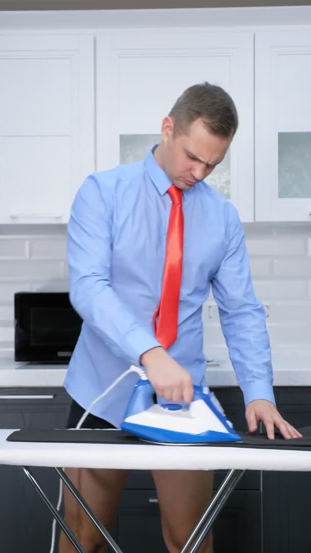 Vertical shot. handsome man in tie ironing trousers — Stock Video