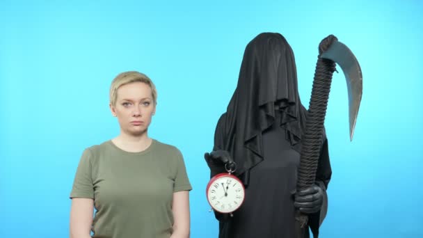 Fantomkép kék háttérrel. A halál megmutatja egy nőnek az órát. — Stock videók