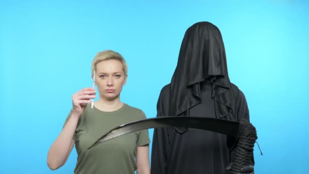 Szene. blauer Hintergrund. die Frau zeigt die Spritze des Todes geht — Stockvideo