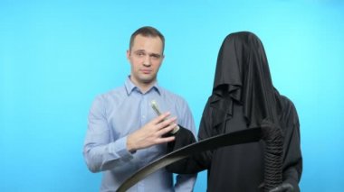 Mavi arka planda bir çizim. Ölüm ve insan. Ölüm insana para verir.