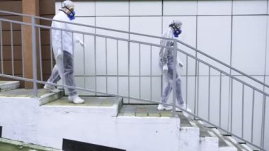 İnsanlar koruyucu giysiler ve solunum cihazlarıyla teknolojik binaların önünden geçiyor