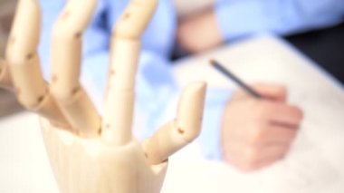 Güzel esmer kız ahşap bir mankenle eskiz çiziyor.