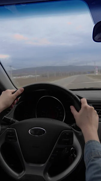 Disparo vertical de las manos femeninas en el volante de un coche en movimiento — Foto de Stock