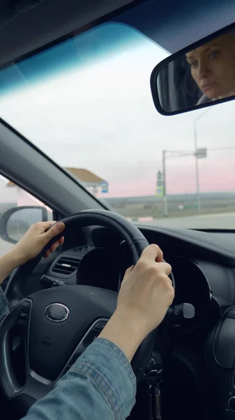 Pionowe ujęcie żeńskich dłoni na kierownicy jadącego samochodu — Zdjęcie stockowe
