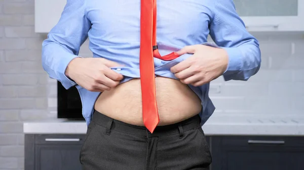 Concepto de pérdida de peso. hombre apenas se abrocha los pantalones, con el estómago grueso —  Fotos de Stock