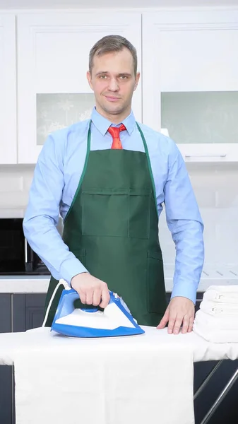 Vertical shot. handsome man in tie and apron stroking linen — 스톡 사진