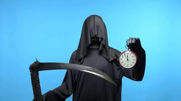 A man in a death suit with a scythe, shows a clock. blue background — 스톡 사진