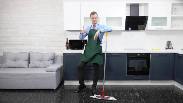 Hombre guapo en corbata y delantal trapea el suelo en la cocina — Foto de Stock