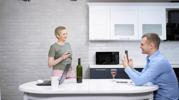 Сучасна домогосподарка і бізнесмен відпочиває і п'є вино на кухні — стокове фото