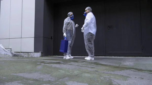 Personas en trajes de protección hablando en la calle frente a una enorme puerta —  Fotos de Stock