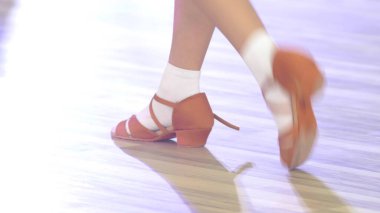 Yakın plan, balo dansı için ayakkabılı çocukların bacakları yerde dans ediyor.