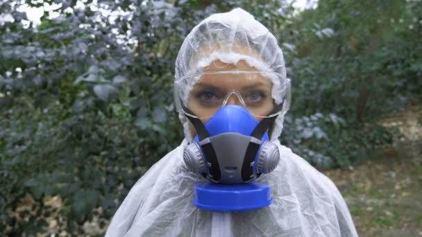 Portrait of a woman in a protective suit and a respirator on nature — Stock Video