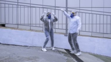 İnsanlar koruyucu giysiler ve solunum cihazlarıyla teknolojik binaların önünden geçiyor