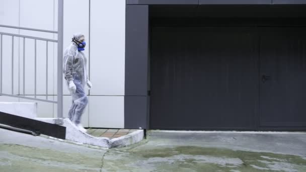 Människor går förbi tekniska byggnader i skyddsdräkter och respiratorer — Stockvideo