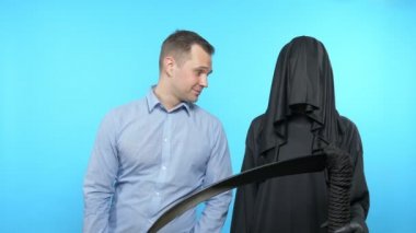 Mavi arka planda bir çizim. Ölüm ve insan. Adam parayla öder.