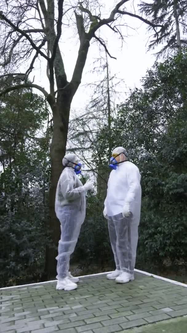 Um homem e uma mulher de fato de protecção e respiradores, vão ao Parque — Vídeo de Stock