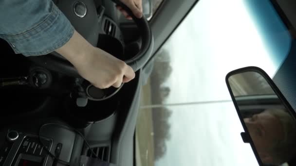 Κάθετη βολή γυναικείων χεριών στο τιμόνι κινούμενου αυτοκινήτου — Αρχείο Βίντεο