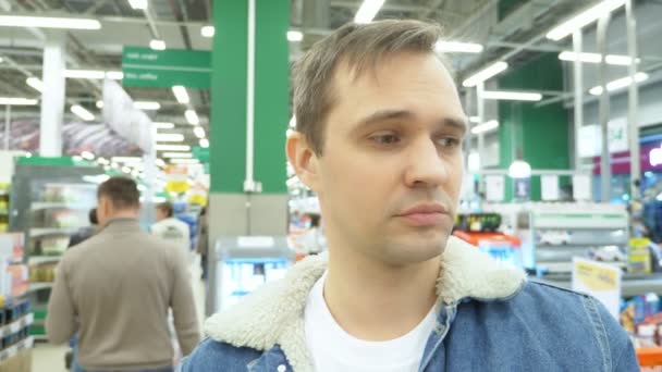 Nahaufnahme. Porträt eines müden Mannes im Supermarkt. Sich umschauen — Stockvideo