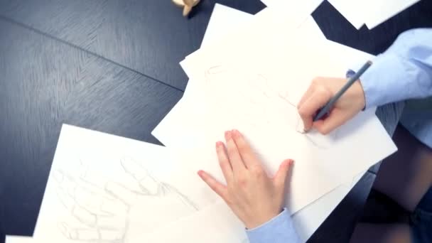 Красивая брюнетка рисует эскиз с деревянным манекеном — стоковое видео