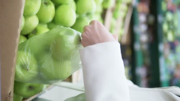 Vertikální výstřel. Detailní záběr rukou. žena sbírá zelená jablka v supermarketu — Stock video