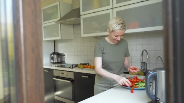 Mujer corta verduras para un aperitivo en la cocina en casa — Vídeo de stock