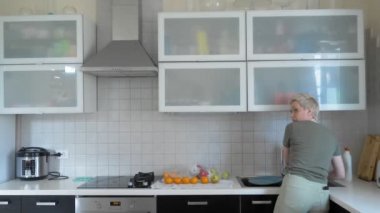 Bir kadın evdeki mutfakta sebze ve meyve yıkıyor..