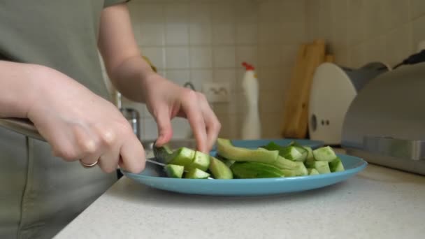 Руки крупным планом женщина разрезала огурец на полоски на кухне — стоковое видео