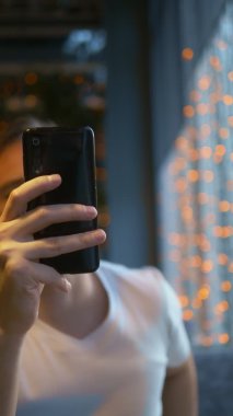 Dikey çekim yapan adam telefondaki mesajı okuduktan sonra nişan yüzüğünü çıkartıyor.