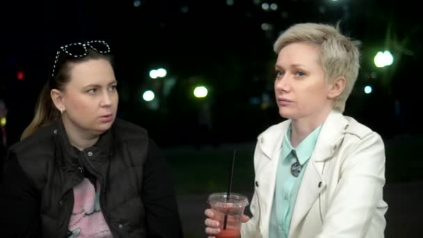 Dos mujeres hablando en la calle por la noche, bebiendo cócteles — Vídeo de stock