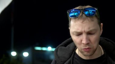 Yakın plan. Tavuk kanadı yiyen bir adam akşamları dışarıda bir kafede oturuyor.