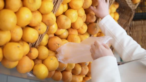 Verticaal schot. Een close-up. vrouw pikt mandarijnen in een supermarkt — Stockvideo