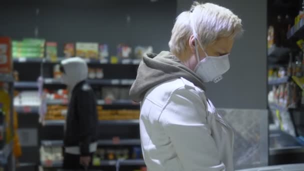 Kortharige blonde vrouw met medisch masker in de supermarkt. pandemie — Stockvideo