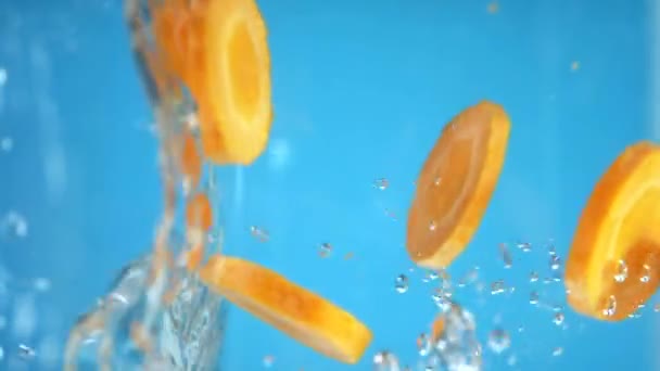 Vertical. zanahorias picadas caen al agua. fondo azul . — Vídeos de Stock