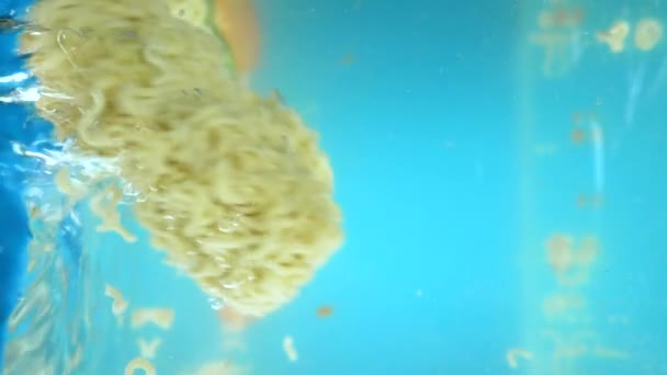 Vertical. chopped vegetables and instant noodles fall into the water. — Stock Video