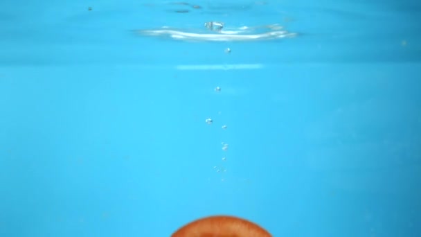 Tomates picados caen en el agua. fondo de cocina azul — Vídeo de stock
