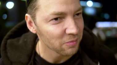 Yakın plan. Tavuk kanadı yiyen bir adam akşamları dışarıda bir kafede oturuyor.