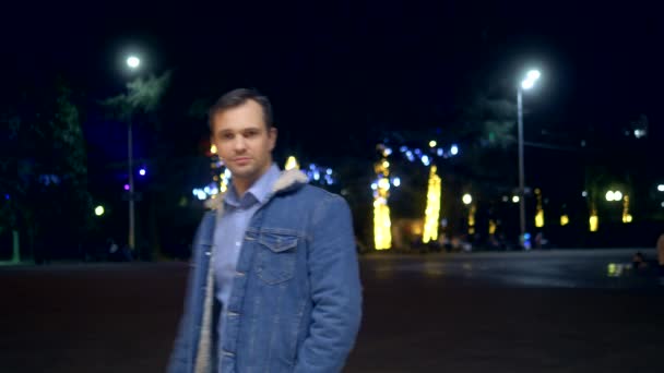 Homem bonito no casaco em uma rua da cidade à noite olhando para a câmera — Vídeo de Stock
