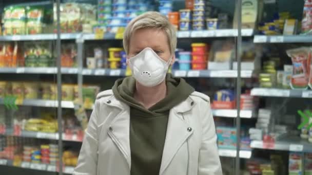 Коротковолосая блондинка в медицинской маске в продуктовом магазине. пандемия — стоковое видео