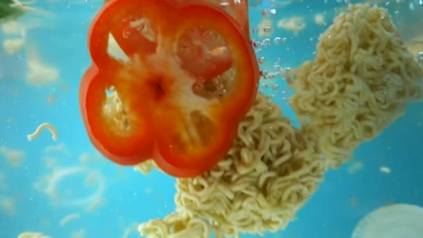 Légumes hachés et nouilles instantanées tombent dans l'eau . — Video