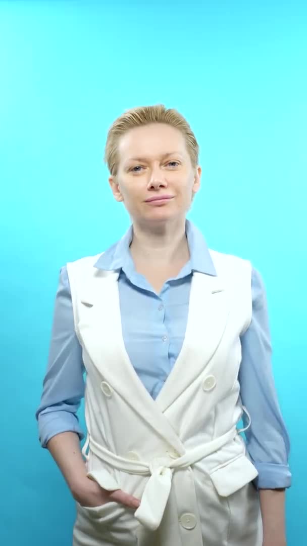 Plan vertical. femme blonde sans maquillage sur fond bleu. signe super — Video